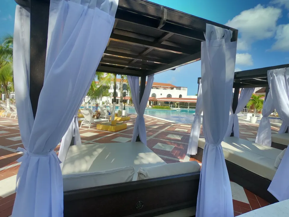Close-up of a shaded cabana with white curtains overlooking the pool at Cozumel Hotel & Resort