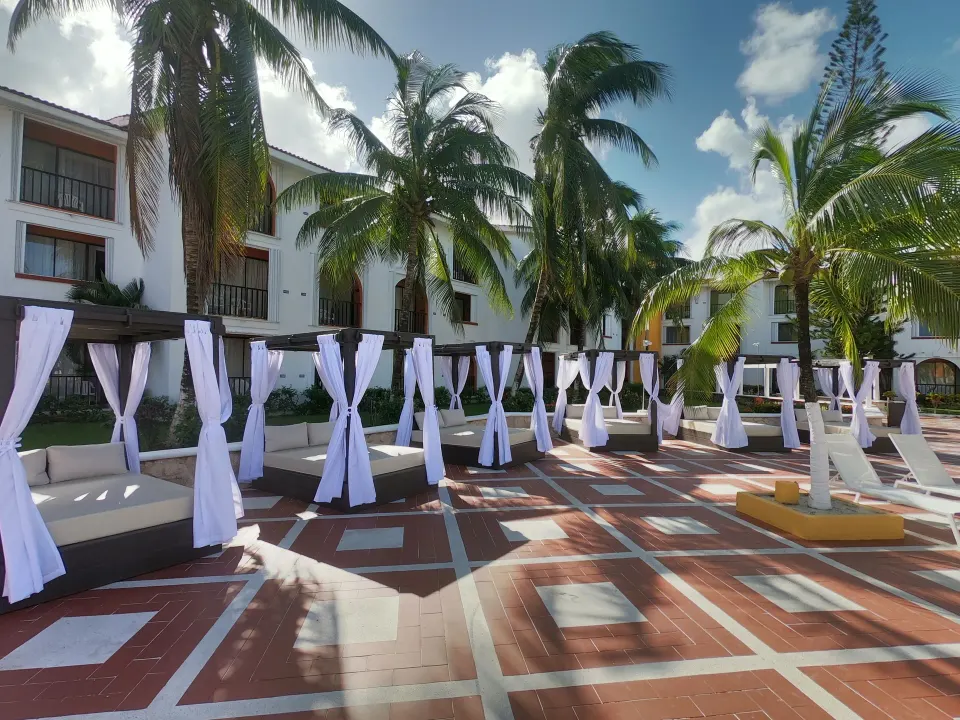 Poolside day scene with cabanas, lounge chairs, and palm trees at Cozumel Hotel & Resort