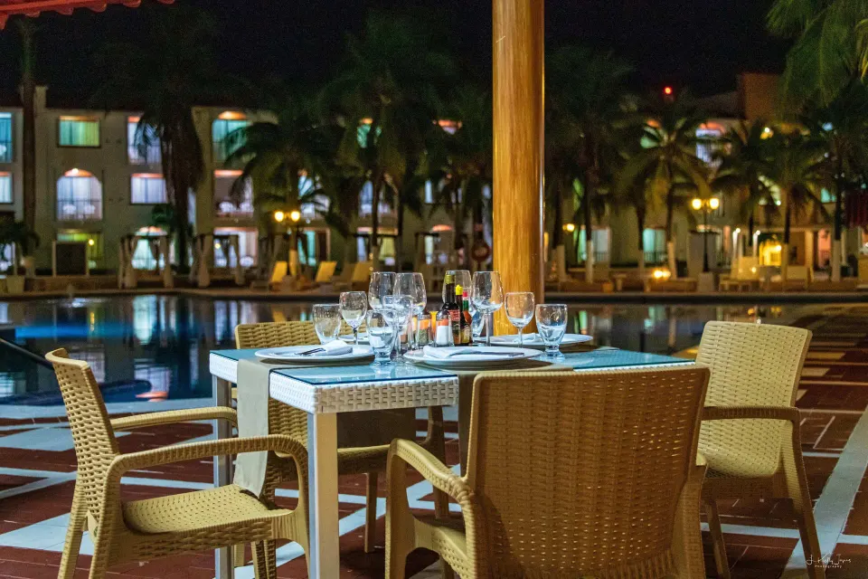 Poolside table set for dinner at night beside the illuminated resort pool at Cozumel Hotel & Resort