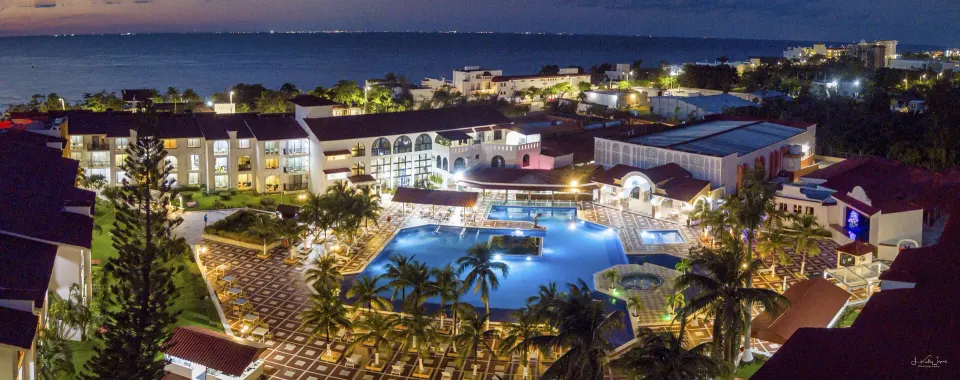 Panoramic evening view of the resort grounds and illuminated pool at Cozumel Hotel & Resort