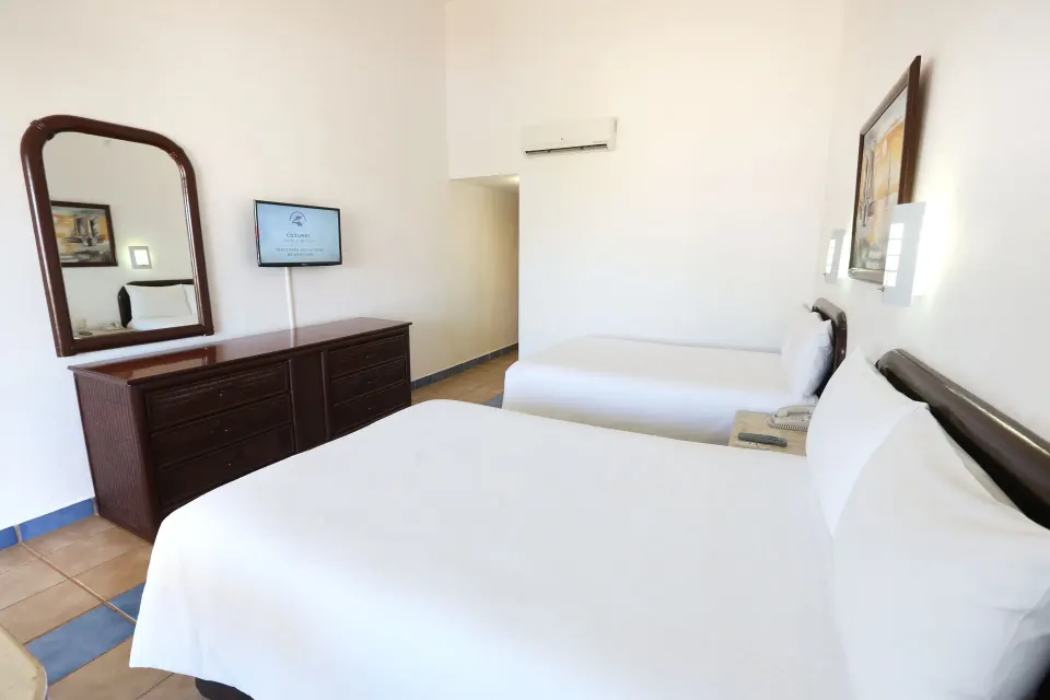 Guest room with a king bed and an extra single bed, dresser and mirror at Cozumel Hotel & Resort