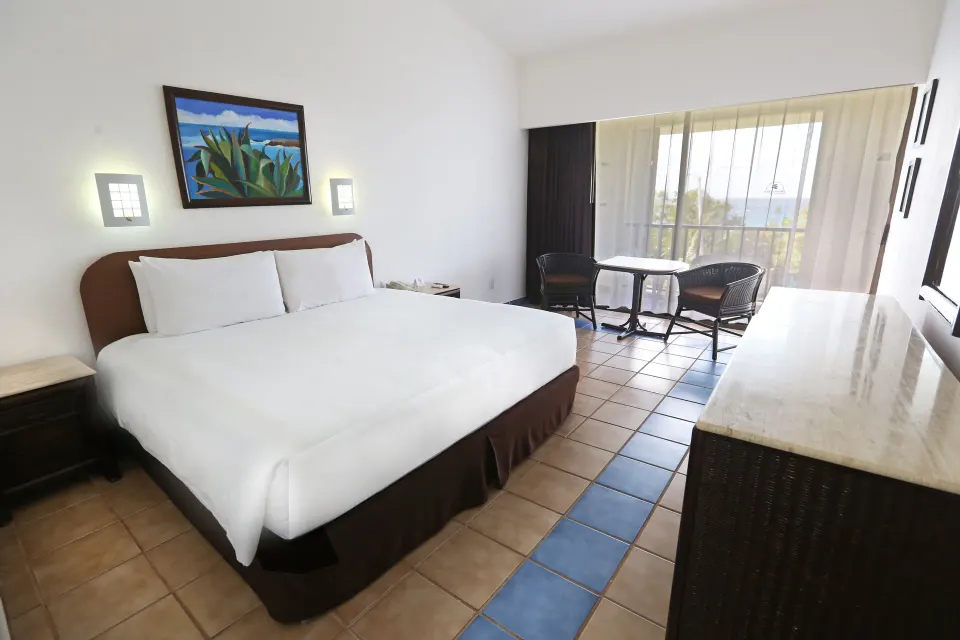 King bed in a guest room with balcony seating and sliding glass doors at Cozumel Hotel & Resort