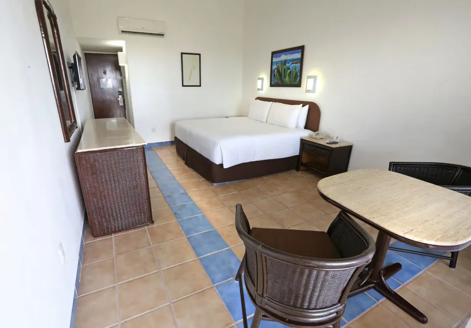 Guest room with a king bed, desk and tiled floor at Cozumel Hotel & Resort
