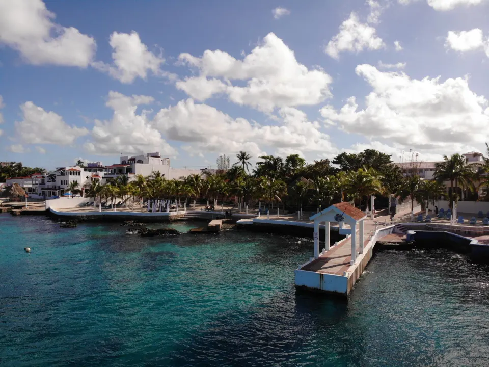 Resort waterfront and pier with tropical palms and blue ocean at Cozumel Hotel & Resort