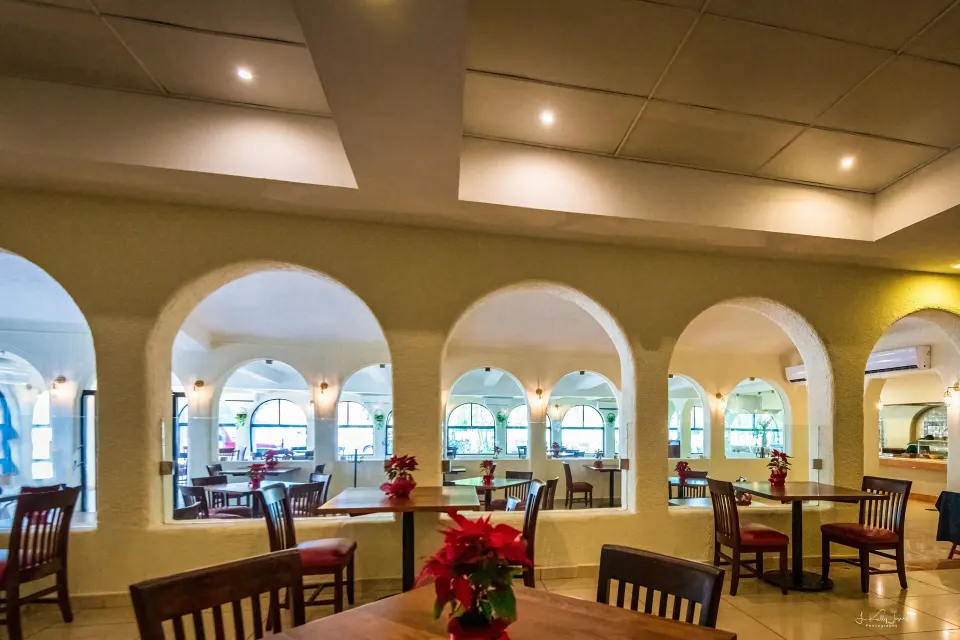 Interior restaurant view showing arches, tables and poinsettia centerpieces at Cozumel Hotel & Resort