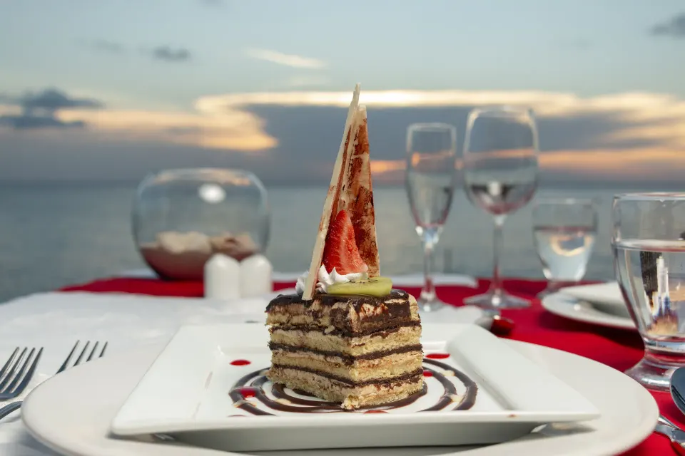 Layered dessert on a plate with ocean sunset in the background at Cozumel Hotel & Resort