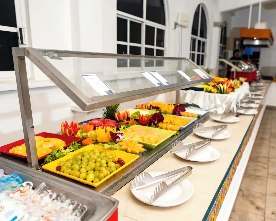 Buffet line with fresh cut fruit displayed under a sneeze guard at Cozumel Hotel & Resort