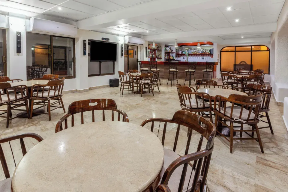 Indoor bar and dining area with wooden chairs and tables at Cozumel Hotel & Resort