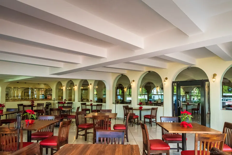 Bright indoor dining room with wooden tables and arches at Cozumel Hotel & Resort