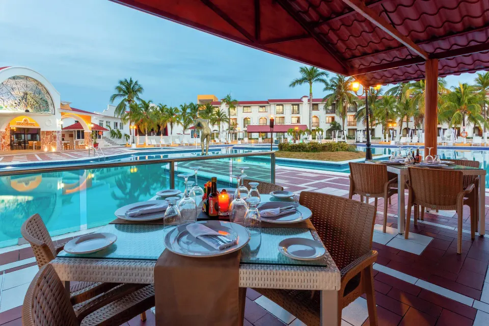 Poolside restaurant tables set for dinner overlooking the resort pool at Cozumel Hotel & Resort.