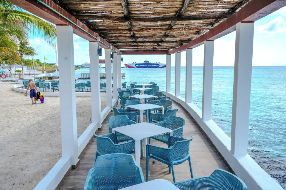 Covered seaside dining walkway with tables facing the ocean at Cozumel Hotel & Resort.