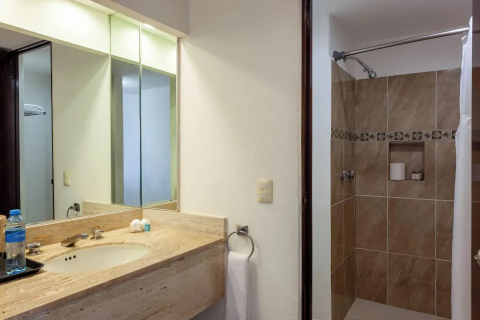 Bathroom vanity and tiled shower in a standard room at Cozumel Hotel & Resort.