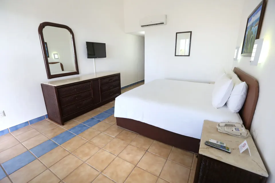 King bed and dresser with mirror in a standard room at Cozumel Hotel & Resort.