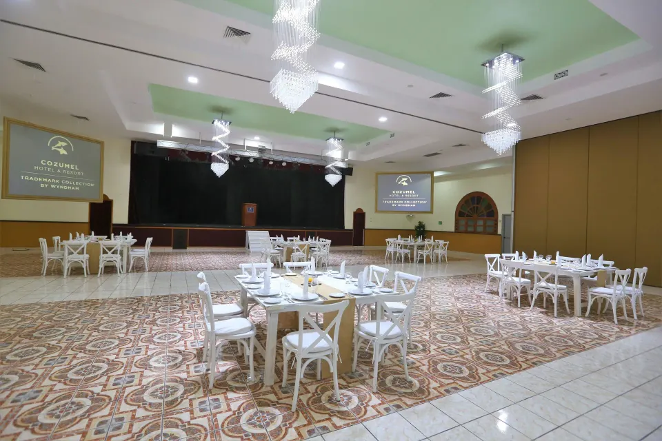 Large ballroom with stage and round dining tables at Cozumel Hotel & Resort