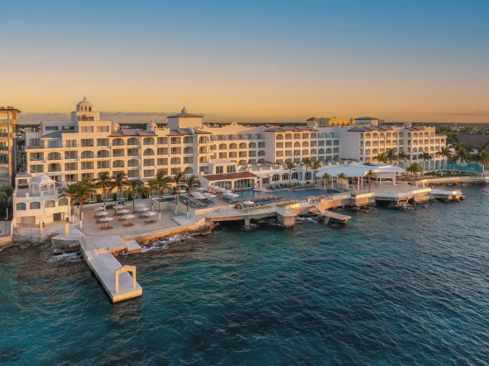 Aerial view of Cozumel Palace resort and its pier along the coastline at sunrise