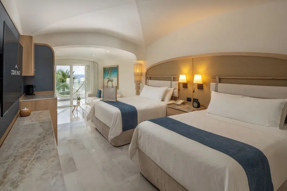 Two double beds facing a TV with balcony and partial ocean view at Cozumel Palace.