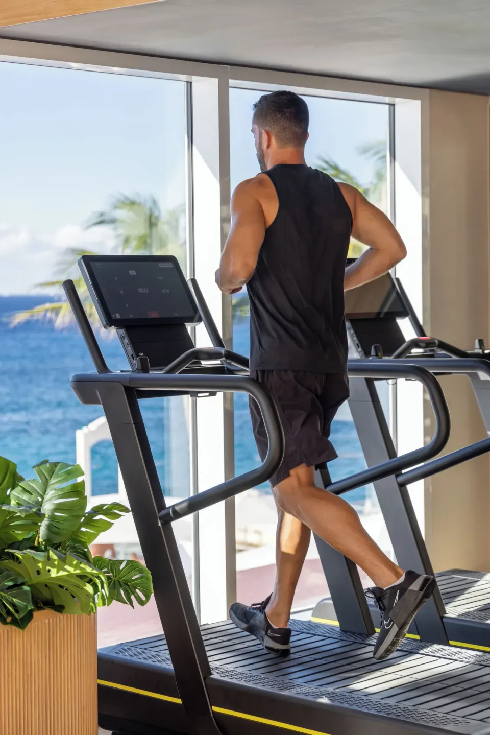 Man running on a treadmill by a window with ocean view at Cozumel Palace