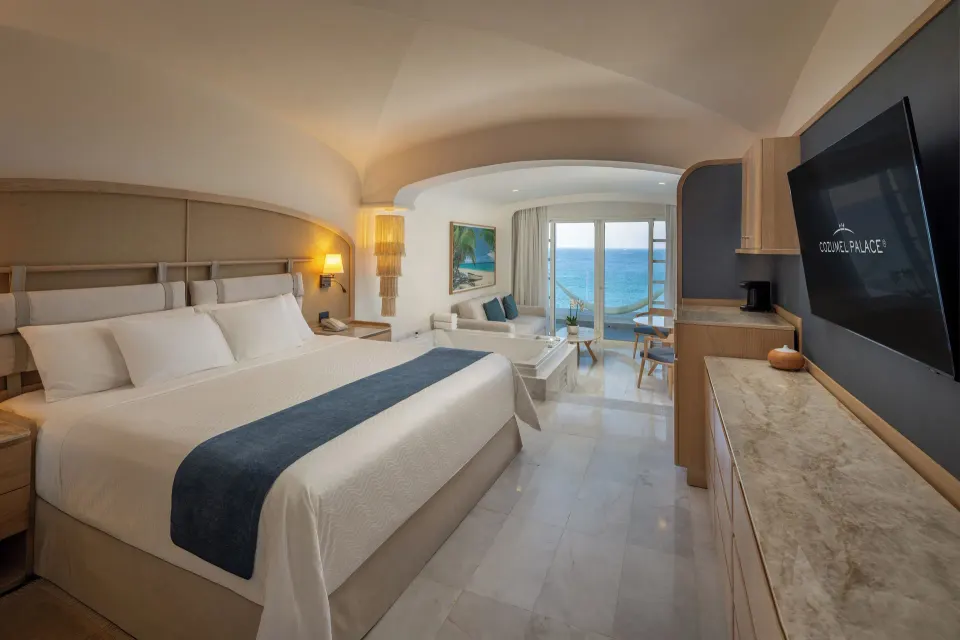 King bed and seating area with ocean view at Cozumel Palace.