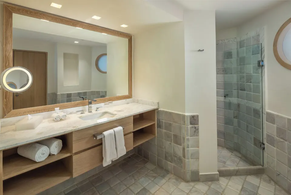 Corner glass shower and marble vanity in a hotel bathroom at Cozumel Palace.