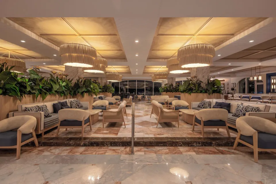 Spacious resort lobby seating area with sofas, chairs and hanging lights at Cozumel Palace.