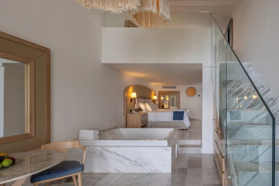 Loft-style guest suite with in-room bathtub and bedroom beyond at Cozumel Palace.