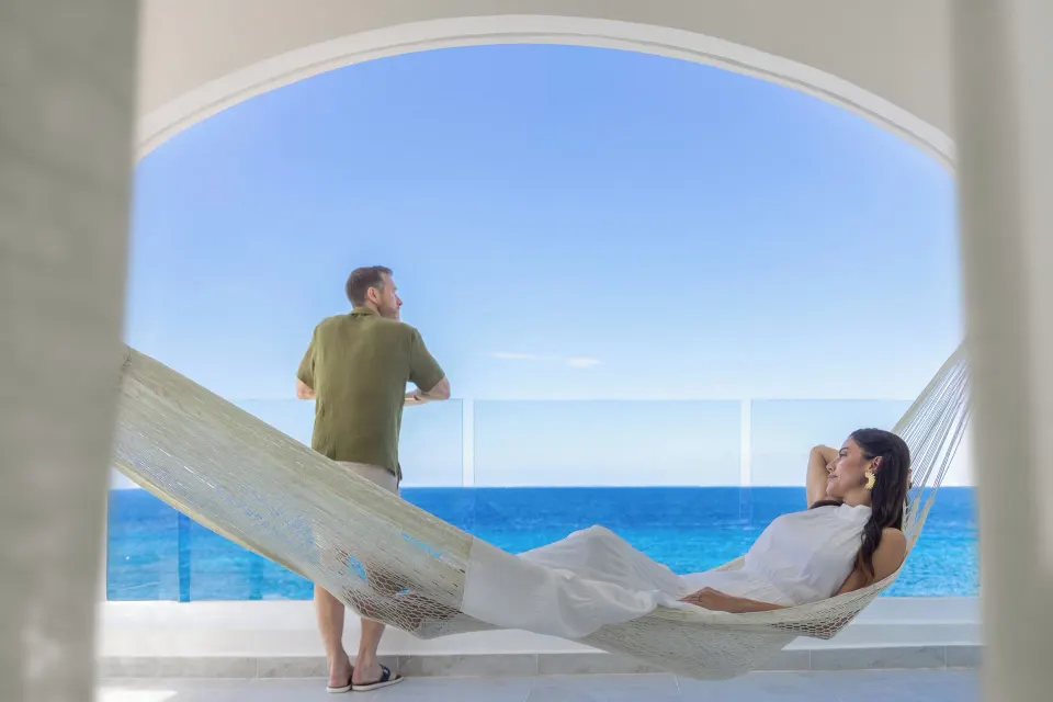 Couple on a balcony hammock overlooking the ocean at Cozumel Palace