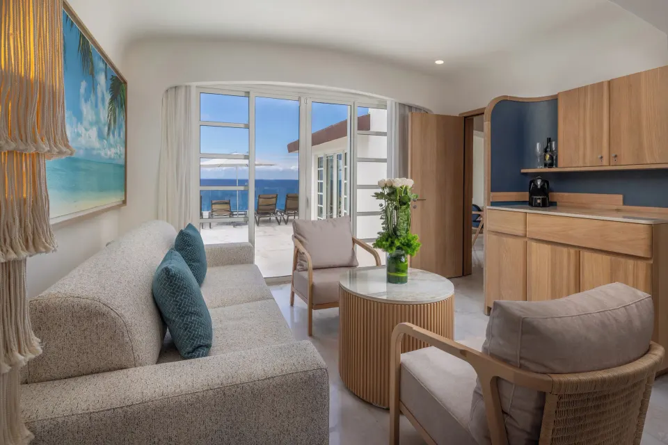 Suite sitting area with sofa and kitchenette opening to balcony at Cozumel Palace.
