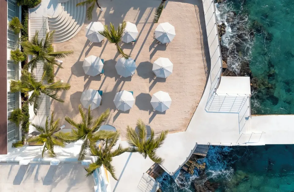 Overhead terrace with white umbrellas and palm trees on the waterfront at Cozumel Palace
