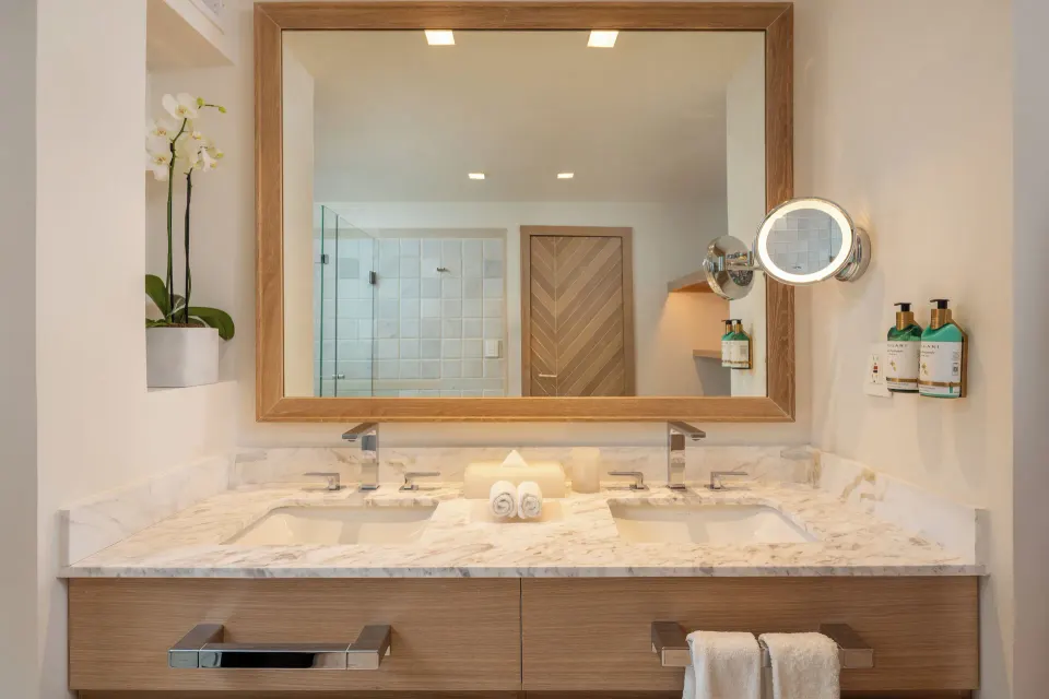 Double vanity with mounted magnifying mirror and dispenser bottles in a bathroom at Cozumel Palace.