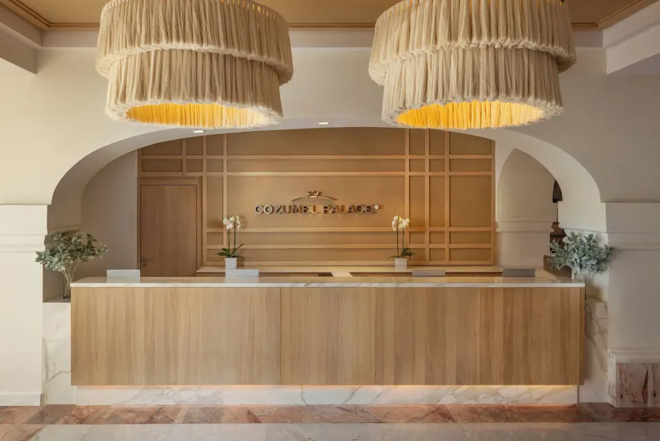 Resort reception desk with wood paneling and pendant lights at Cozumel Palace.