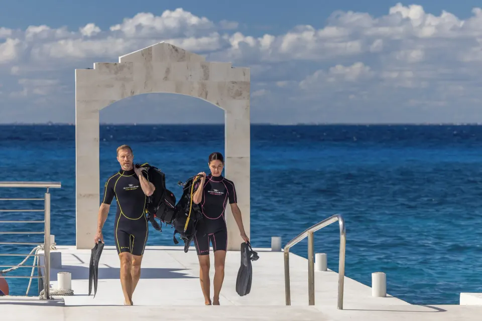 Two scuba divers walking along the resort pier at Cozumel Palace