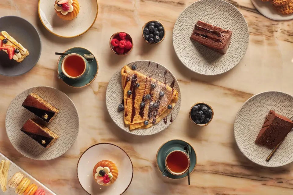 Assorted plated desserts and tea on a marble table at Cozumel Palace