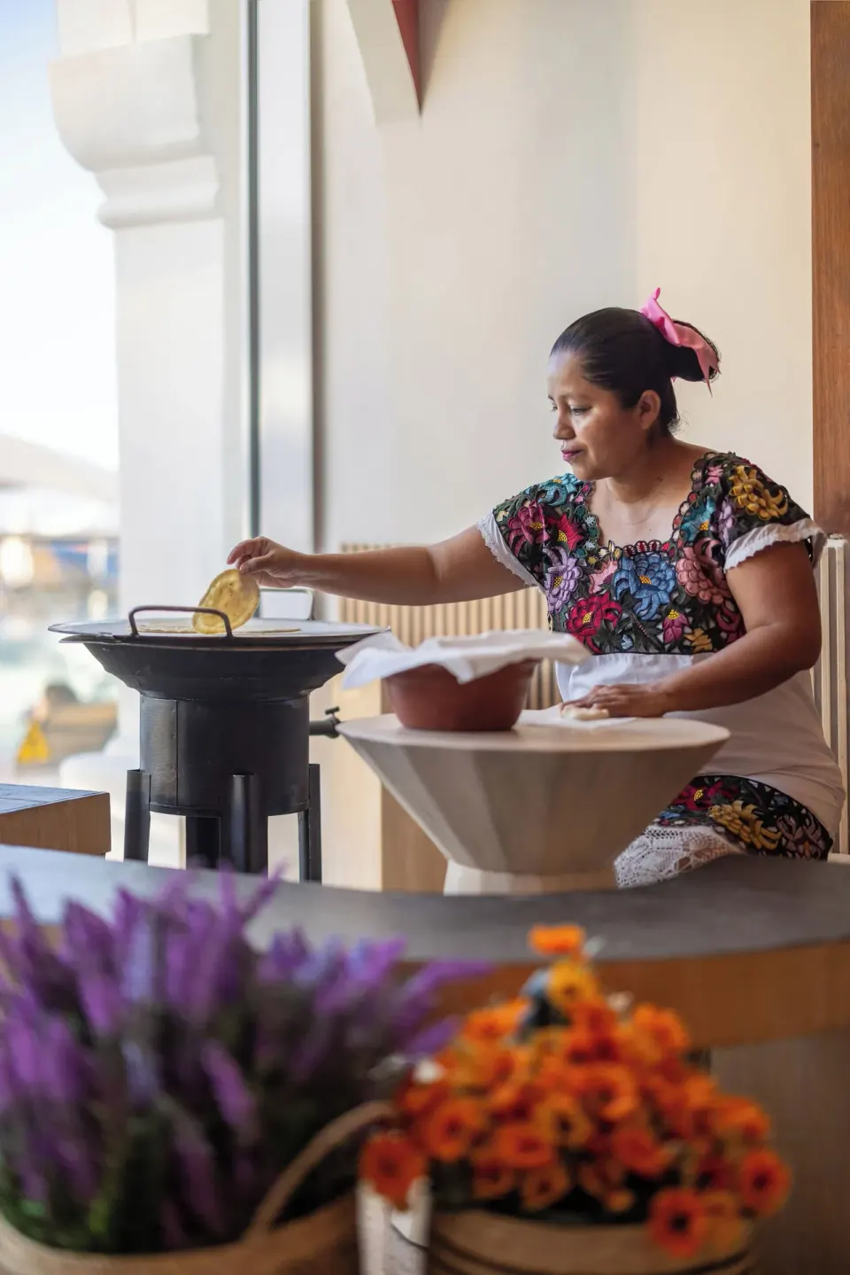 Woman in traditional dress preparing tortillas at Cozumel Palace