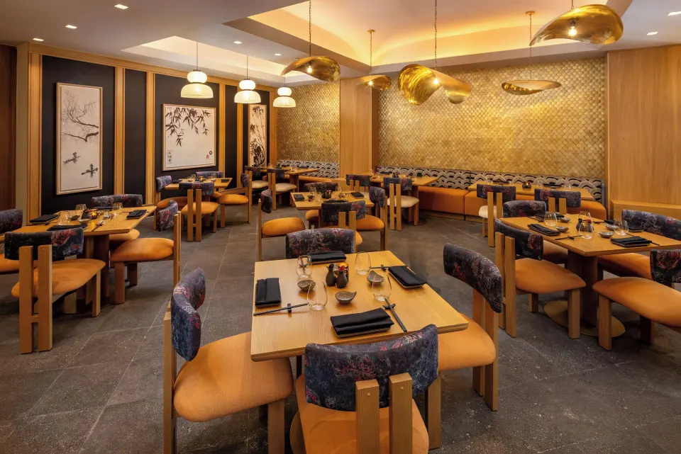Modern Asian-style restaurant interior with wooden tables and gold accents at Cozumel Palace
