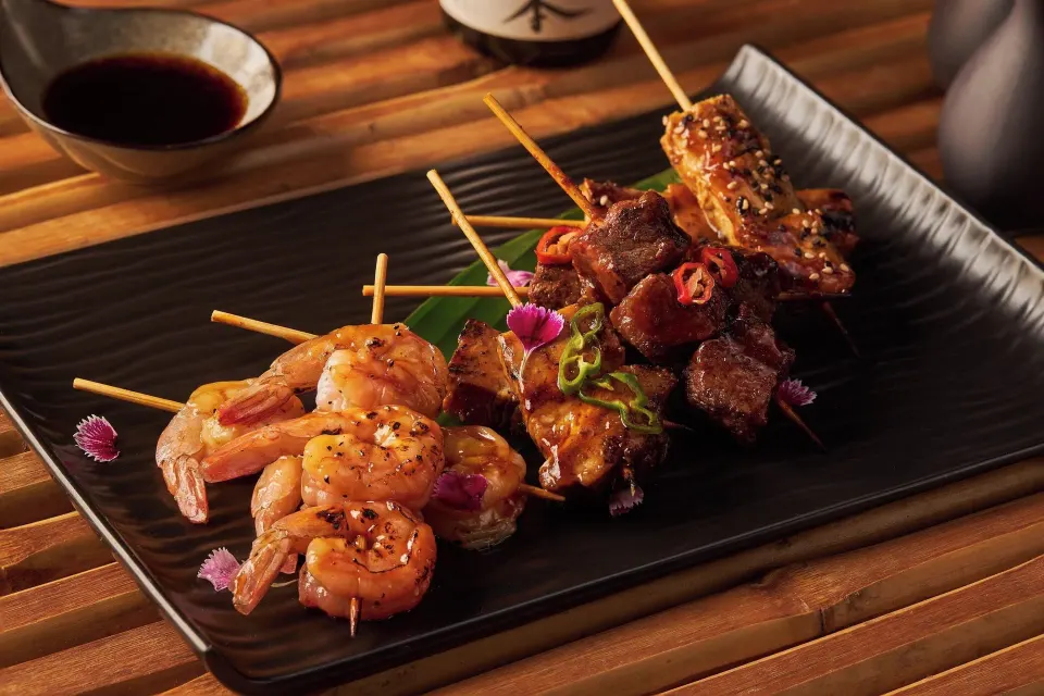 Grilled skewers of shrimp and meat served on a black platter at Cozumel Palace