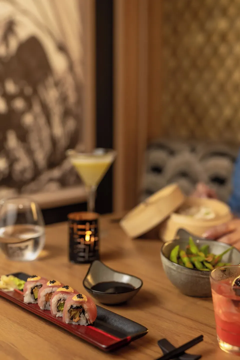 Sushi rolls with edamame and cocktails in a dim dining setting at Cozumel Palace