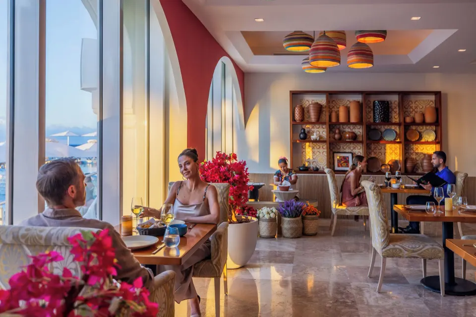 Bright restaurant interior with ocean views and bougainvillea at Cozumel Palace