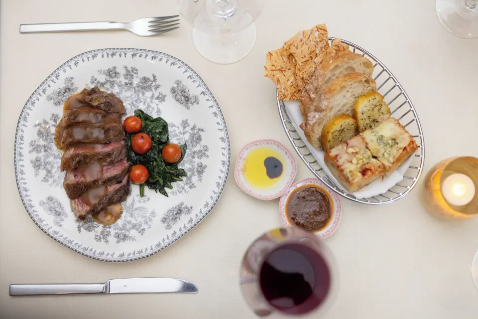 Plated steak with roasted tomatoes and bread basket at Cozumel Palace
