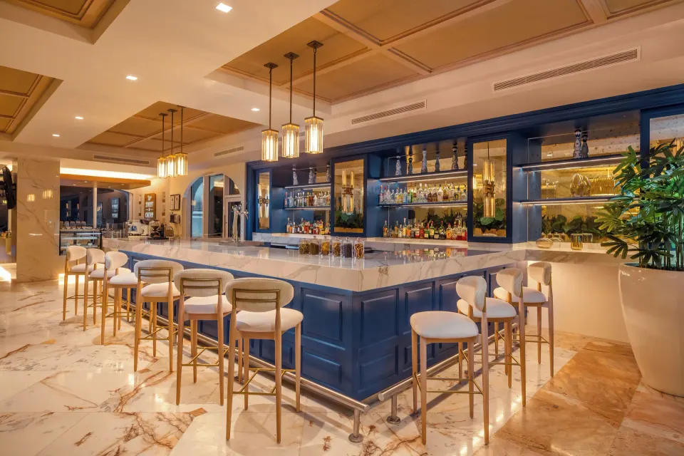 Marble-topped resort bar with blue cabinetry and stools at Cozumel Palace