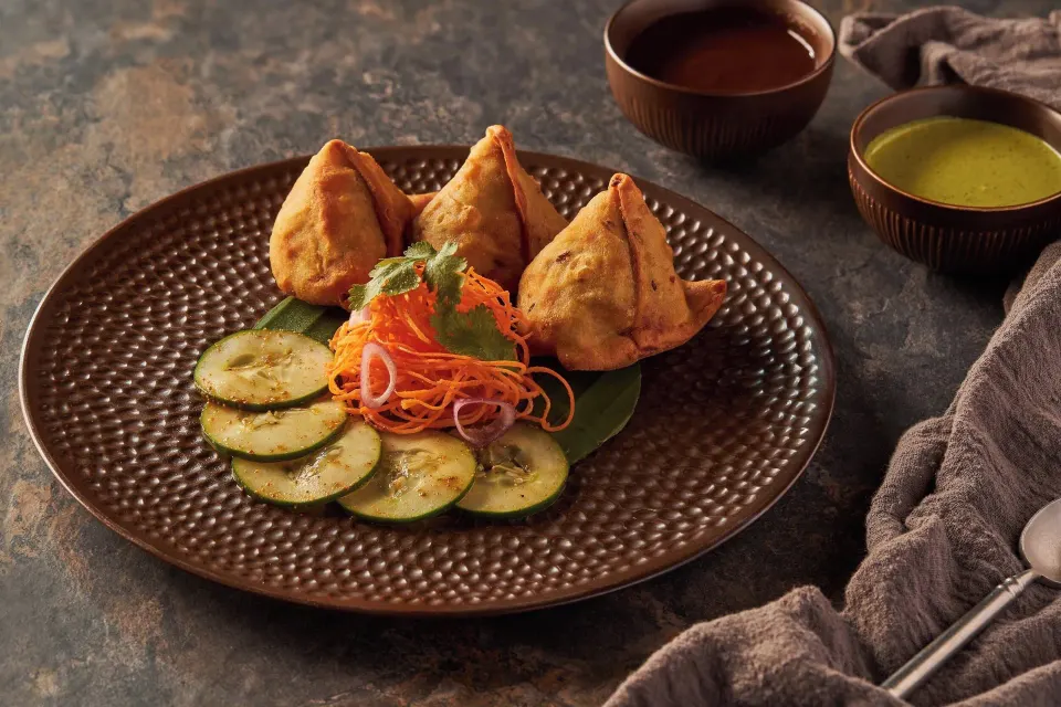 Plate of three samosas with cucumber and dipping sauces at Cozumel Palace
