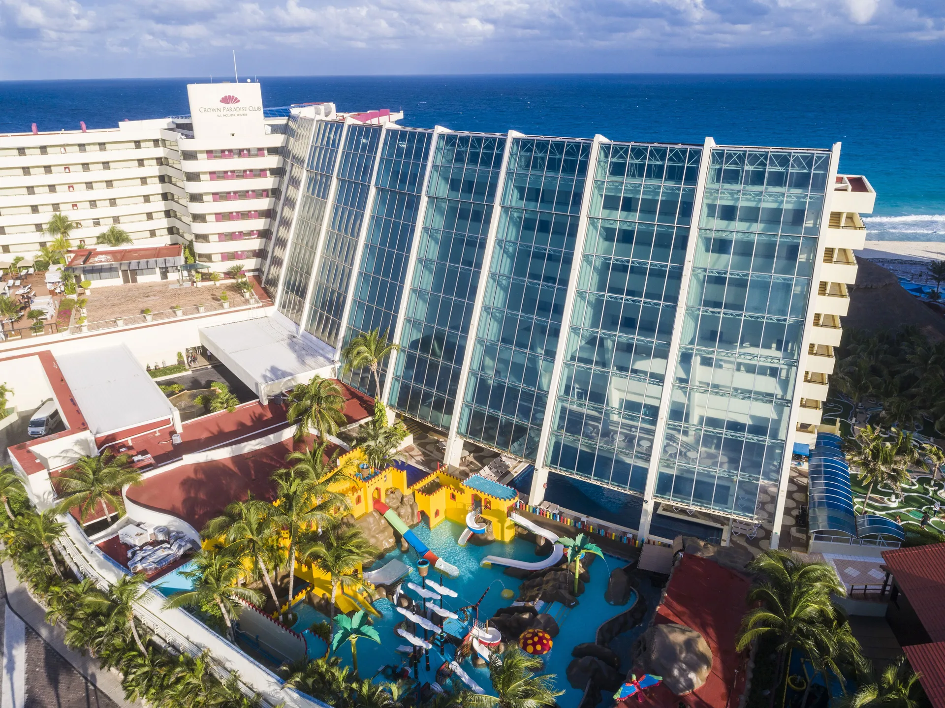 Aerial view of Crown Paradise Club Cancun with glass-fronted buildings and kids water area.