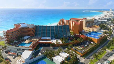 Aerial view of Crown Paradise Club Cancun with beach, pools, and tennis courts.