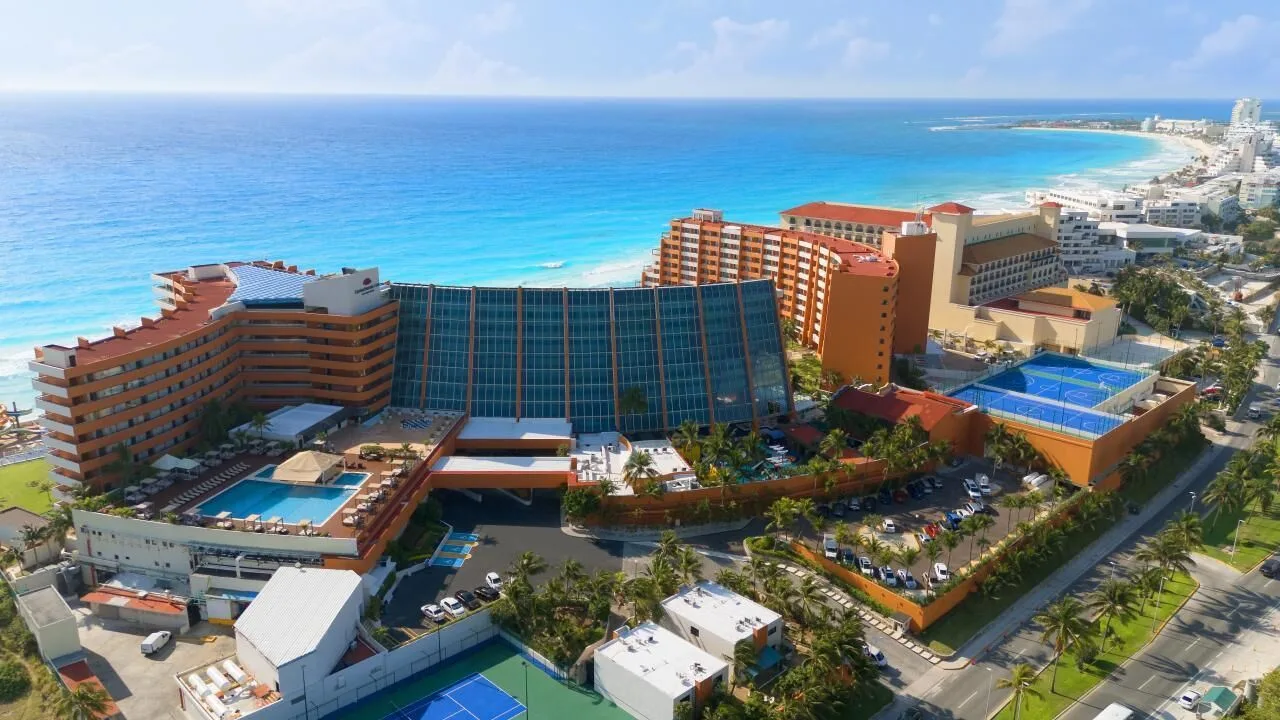 Aerial view of Crown Paradise Club Cancun with beach, pools, and tennis courts.