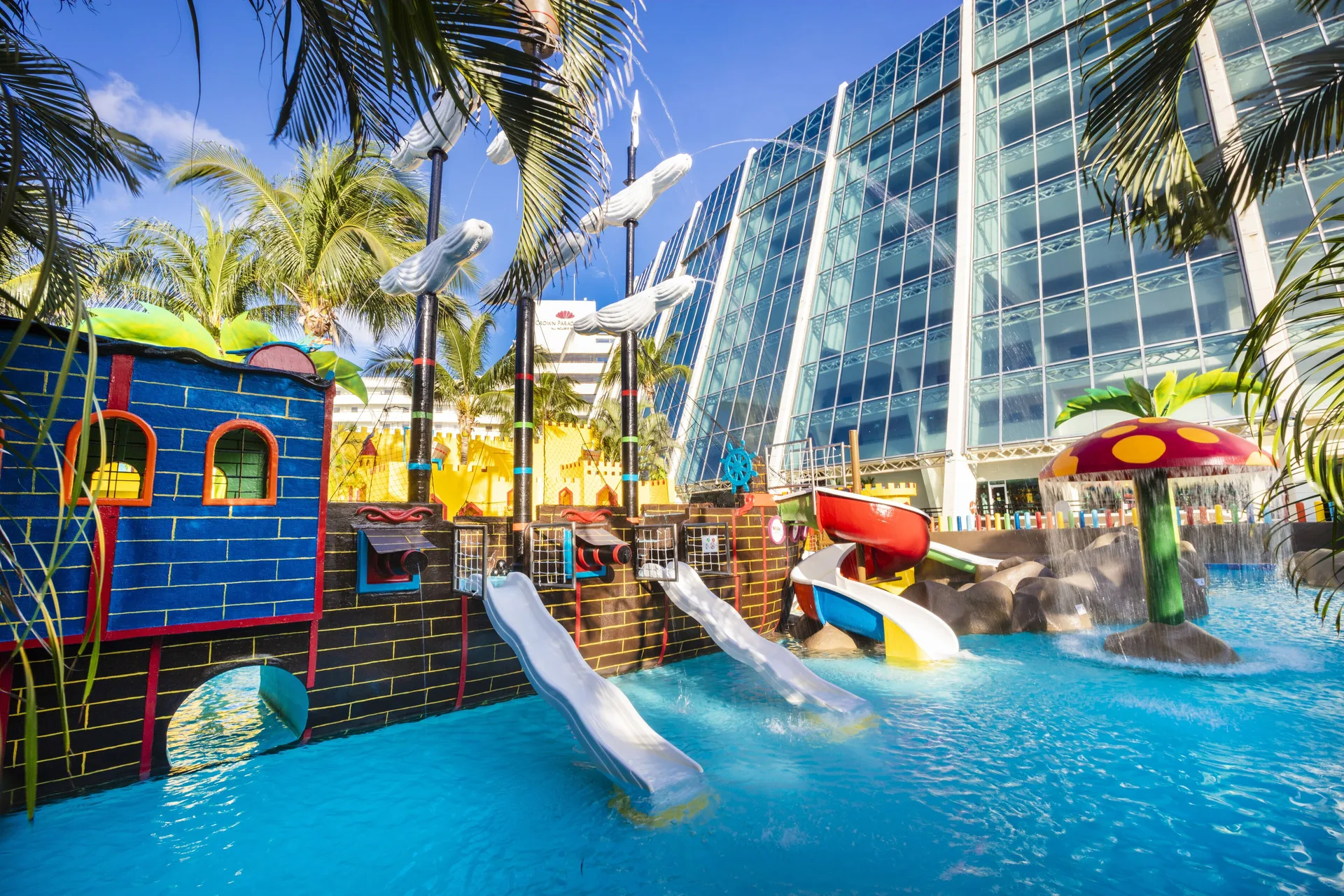 Children’s pirate ship water play area at Crown Paradise Club Cancun with slides and palm trees.
