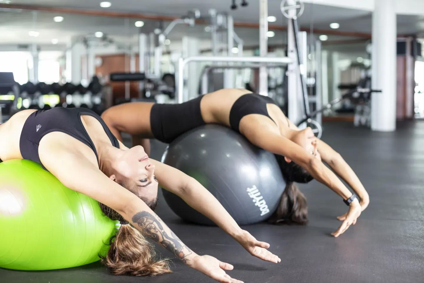 Fitness room at Crown Paradise Club Cancun with two people stretching on exercise balls.