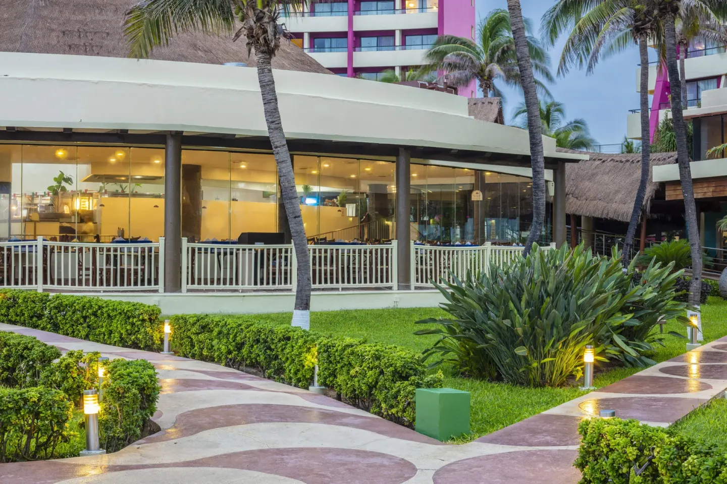 Garden walkways and glass-walled resort building at Crown Paradise Club Cancun.