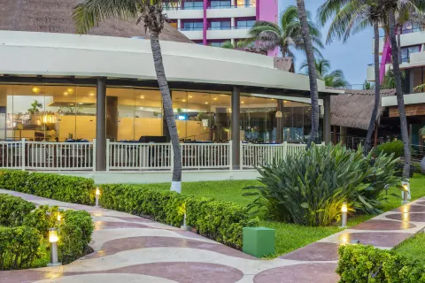 Garden walkways and glass-walled resort building at Crown Paradise Club Cancun.