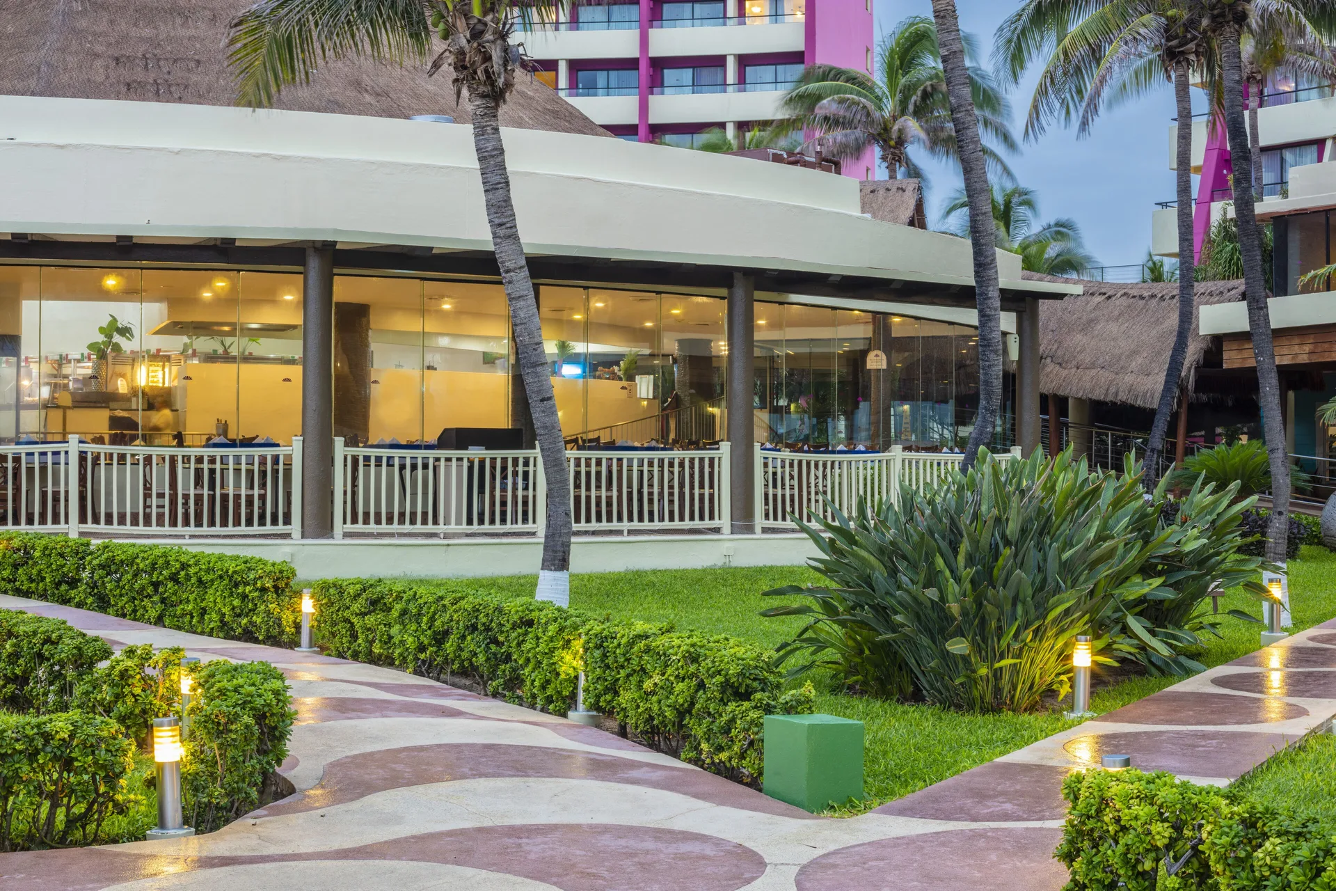 Garden walkways and glass-walled resort building at Crown Paradise Club Cancun.