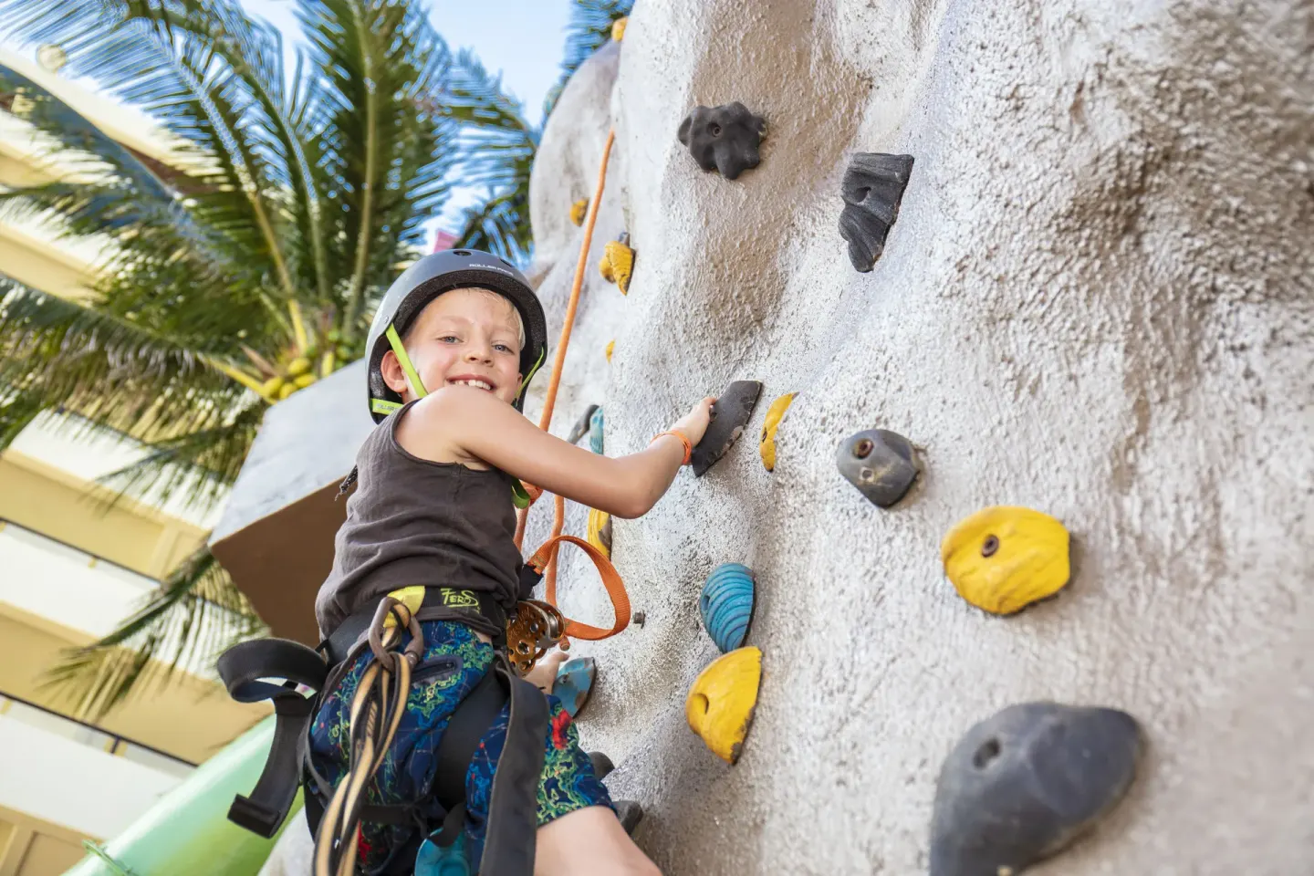 Child climbing an outdoor rock wall at Crown Paradise Club Cancun.
