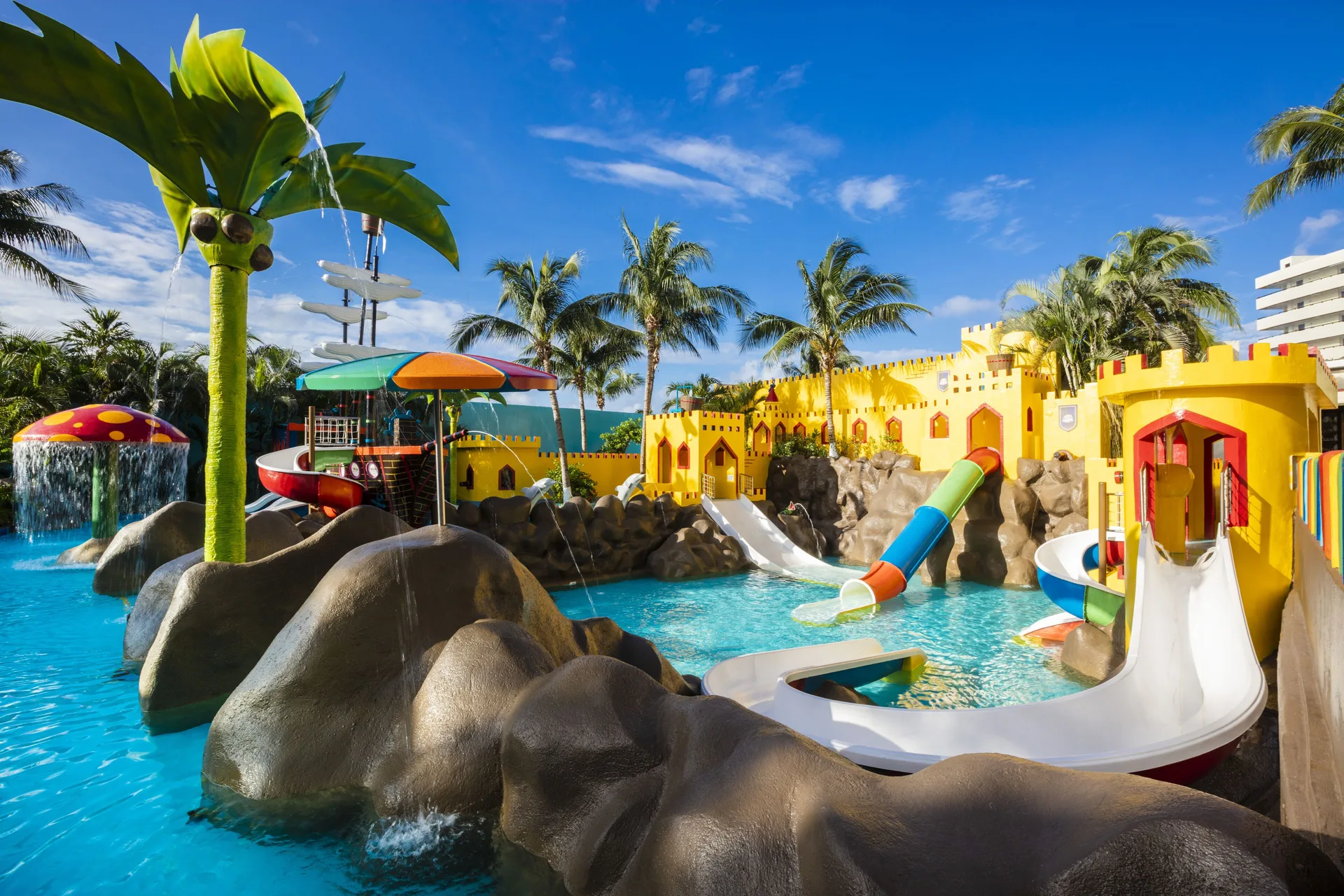 Kids’ water park at Crown Paradise Club Cancun with slides, splash features, and palm trees.